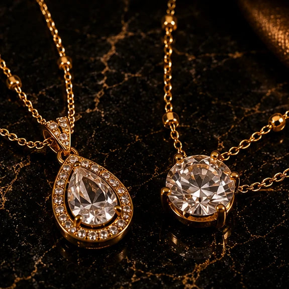 Vellery gold necklaces with crystal pendants on black marble